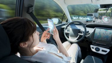 Woman using phone while sitting in the driver's seat of self-driving cars